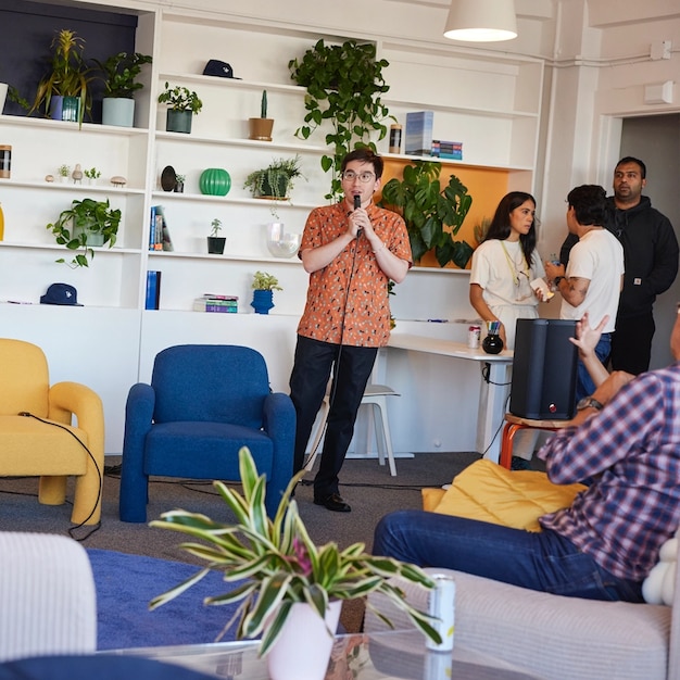 Person in orange patterned shirt speaking at event with white built-in shelving and plants